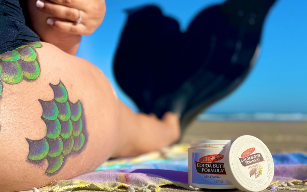 Person with mermaid body art, using Palmer’s Cocoa Butter Formula.