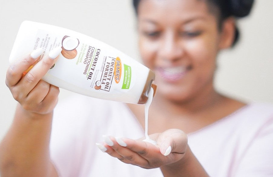 Hands dispensing Palmer’s Coconut Oil Conditioning Shampoo from bottle.
