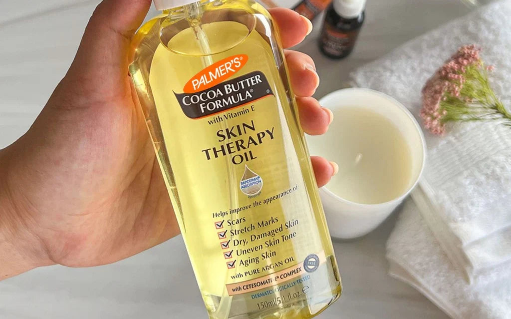A hand holding a bottle of skin therapy oil, showcasing the product's label and design in a close-up view.