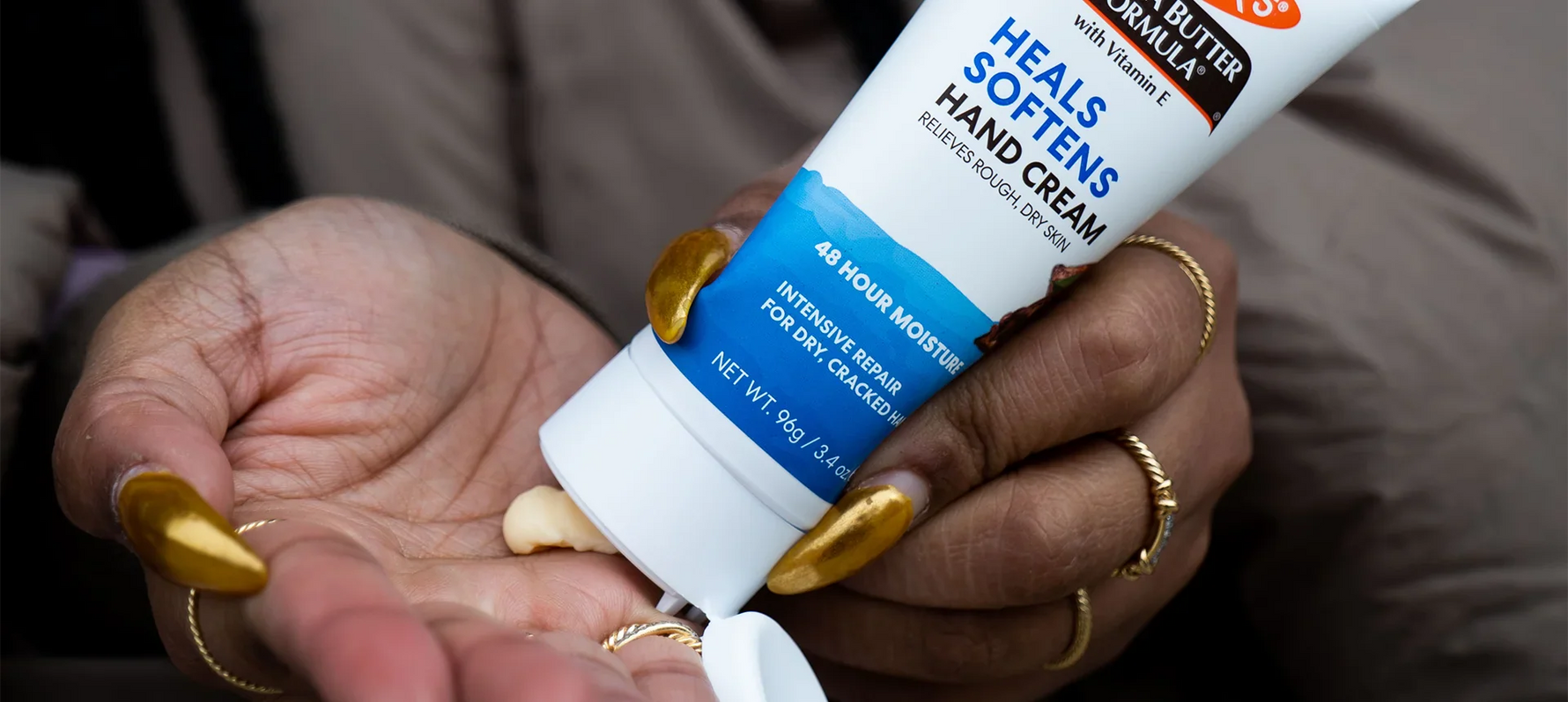 Woman's hands applying Palmer's Cocoa Butter Formula Hand Cream from tube