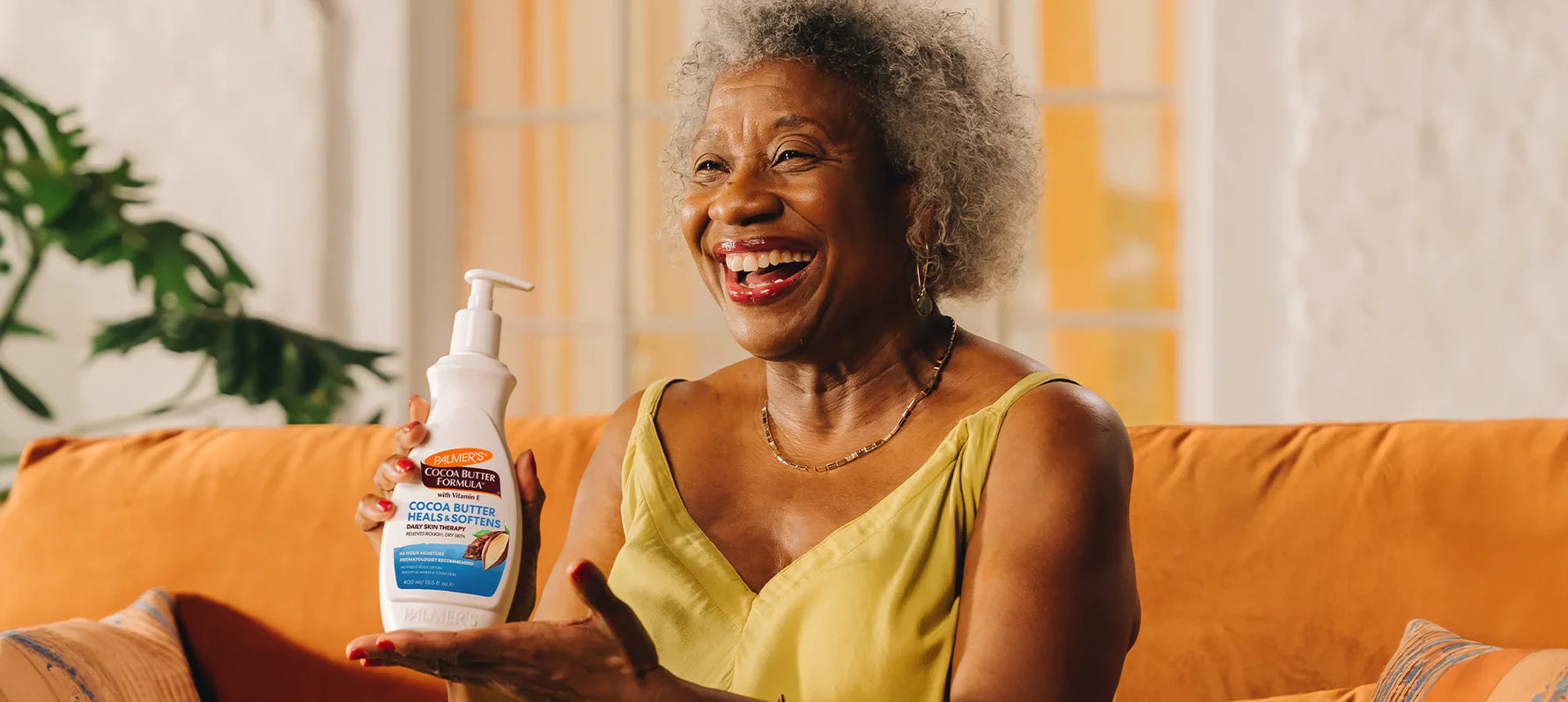 Woman holding Palmer's Coconut Butter Formula Lotion while laughing