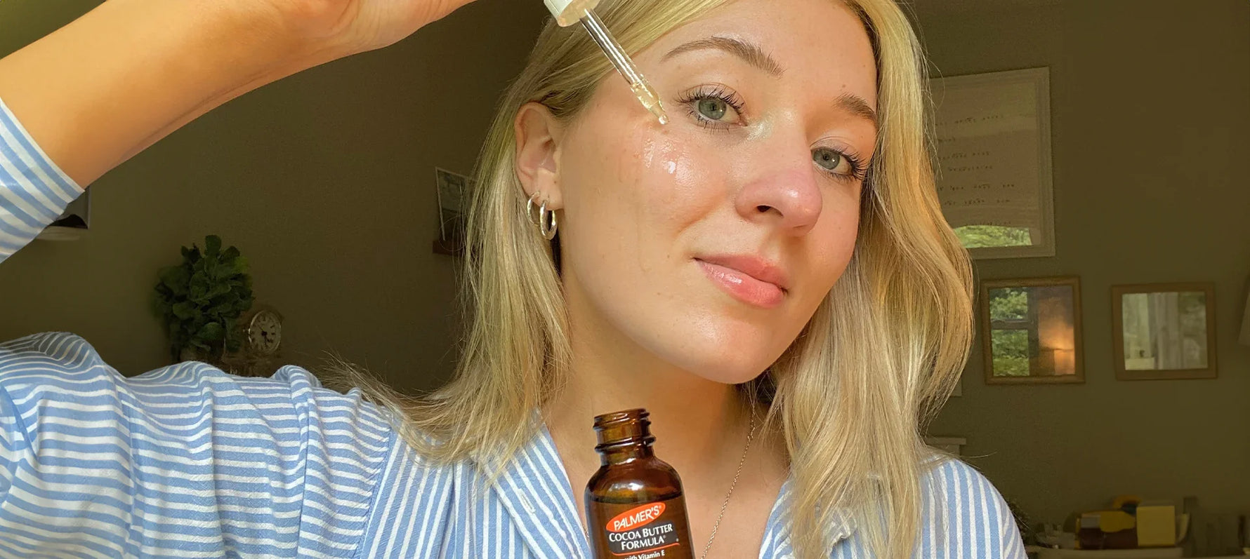 Woman applying Palmer's Skin Therapy Face Oil to her cheek from dropper