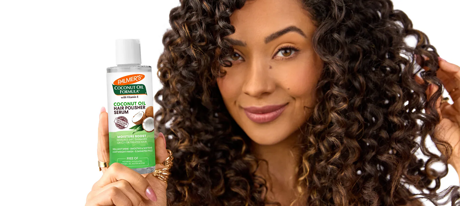 Woman with curly hair holding Palmer's Coconut Oil Hair Polisher Serum
