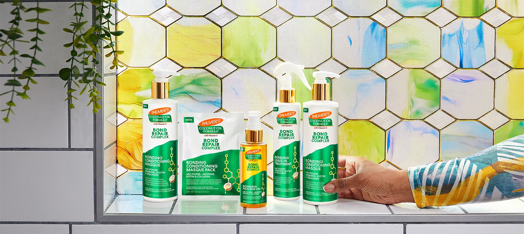 Woman's hand reaching for Palmer's Bond Repair Complex products on window sill
