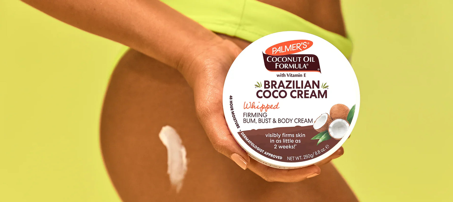 Woman's hand holding Palmer's Brazilian Coco Cream in front of her hip