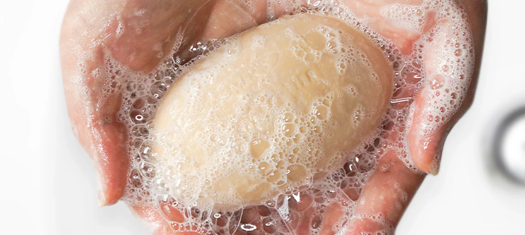 Hands holding bar of Palmer's Cocoa Butter Soap with lather