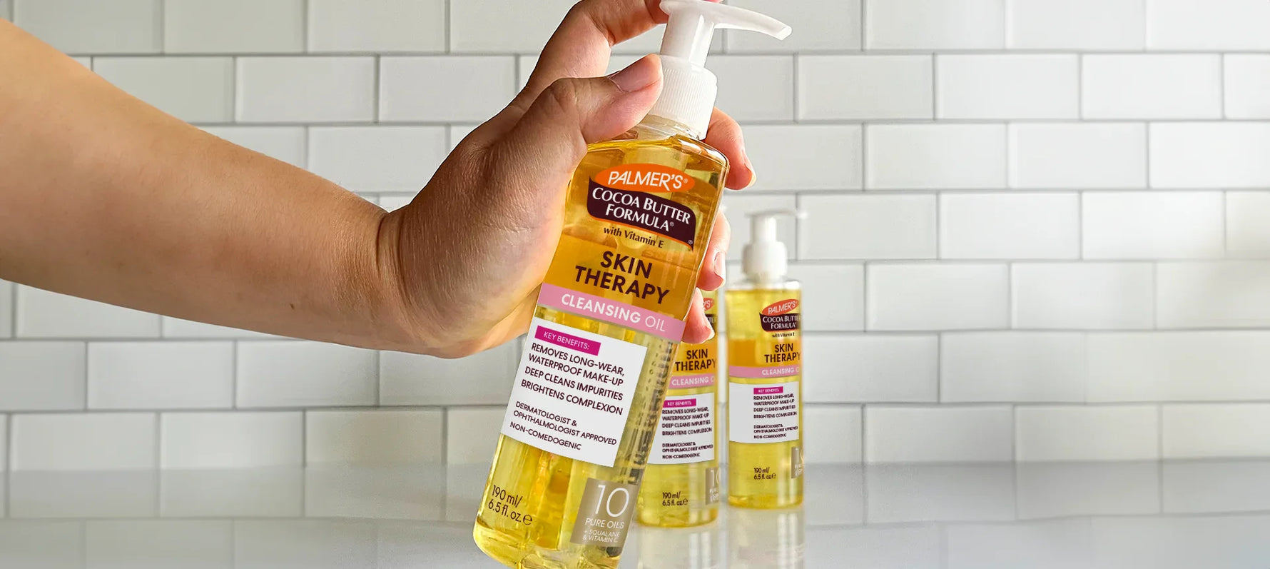 Hand holding bottle of Palmer's Skin Therapy Cleansing Oil in bathroom