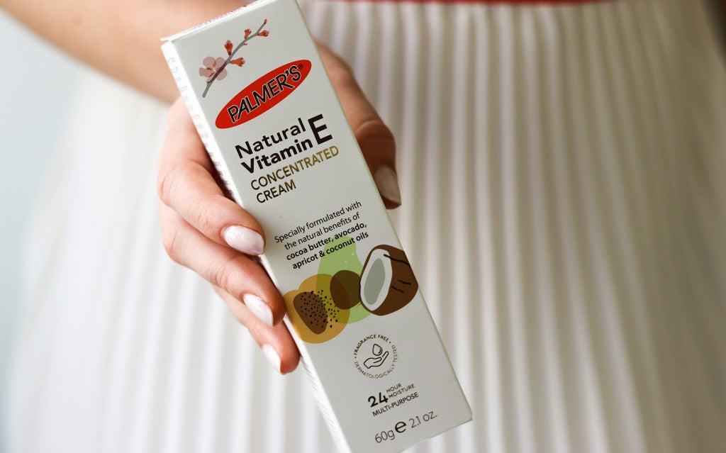 Woman's hand holding Palmer’s Natural Vitamin E Cream.
