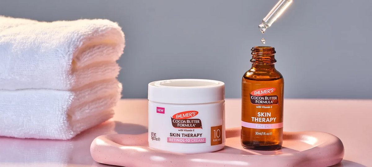 Palmer's Skin Therapy Face Oil and Skin Therapy Retinol-10 Cream on table with dropper and towels