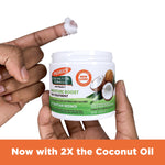 Person holding Palmer's Coconut Oil Gro Treatment jar with cream on fingertip.