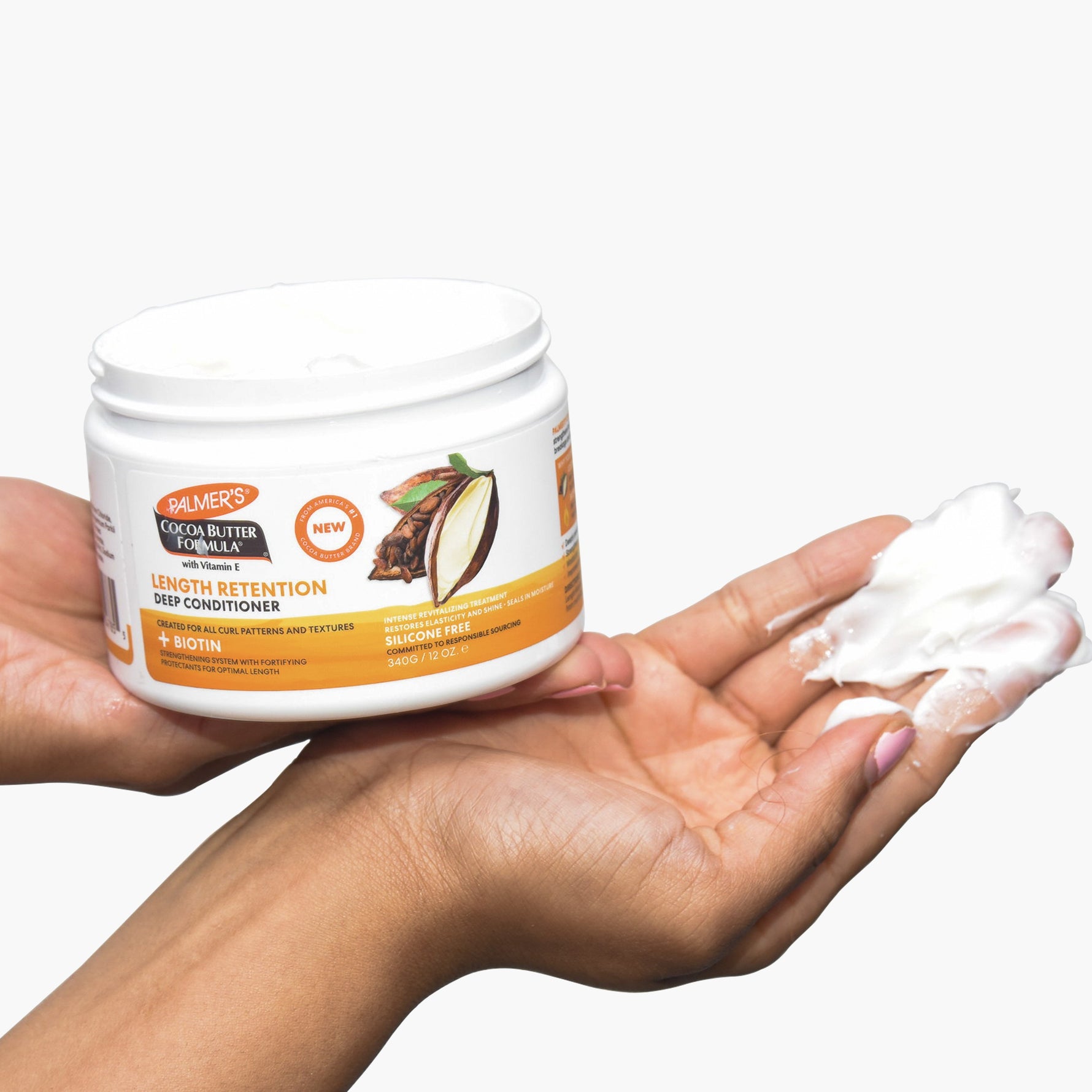 Hand holding Palmer's Cocoa Butter Deep Conditioner with cream dollop.