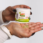 Hands holding Palmer’s Olive Oil Gro Therapy with dollop shown.