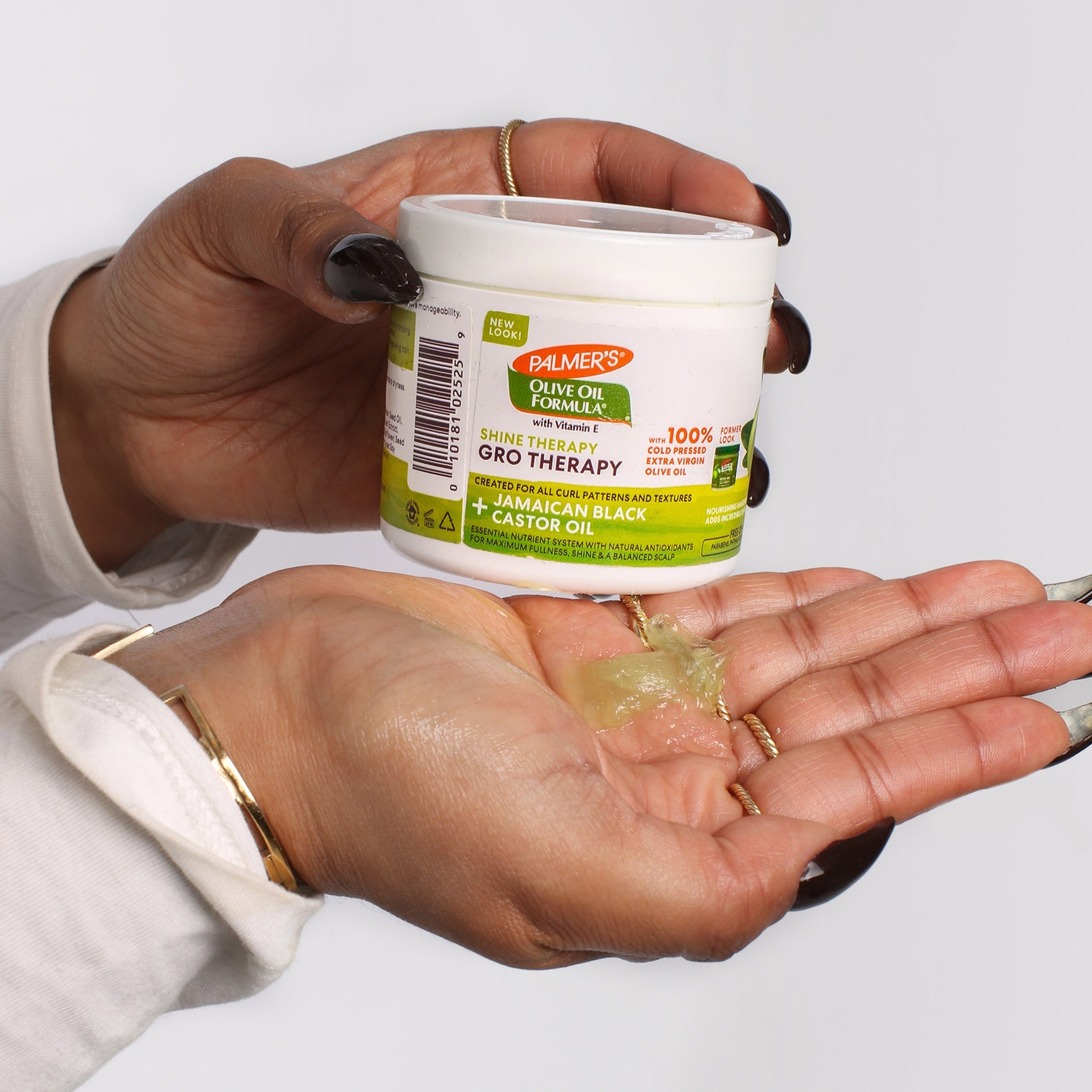 Hands holding Palmer’s Olive Oil Gro Therapy with dollop shown.