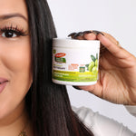 Hand holding Palmer's Olive Oil Gro Therapy jar for nourishing hair treatment.
