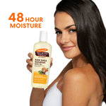 Woman holding Palmer’s Raw Shea Nourish Body Oil, smiling.