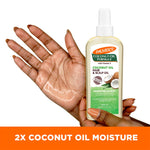 Hand holding Palmer's Coconut Oil Hair & Scalp Oil bottle.