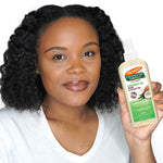 Woman holding Palmer's Coconut Oil Hair & Scalp Oil bottle.