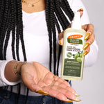 Person holding Palmer’s Olive Oil Hair & Scalp Oil spray bottle.