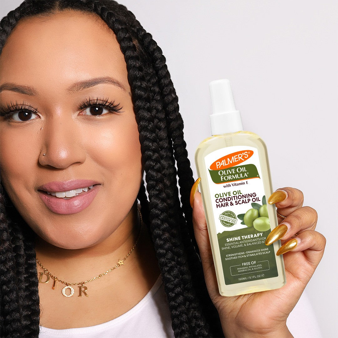 Woman holding Palmer’s Olive Oil Hair & Scalp Oil spray.