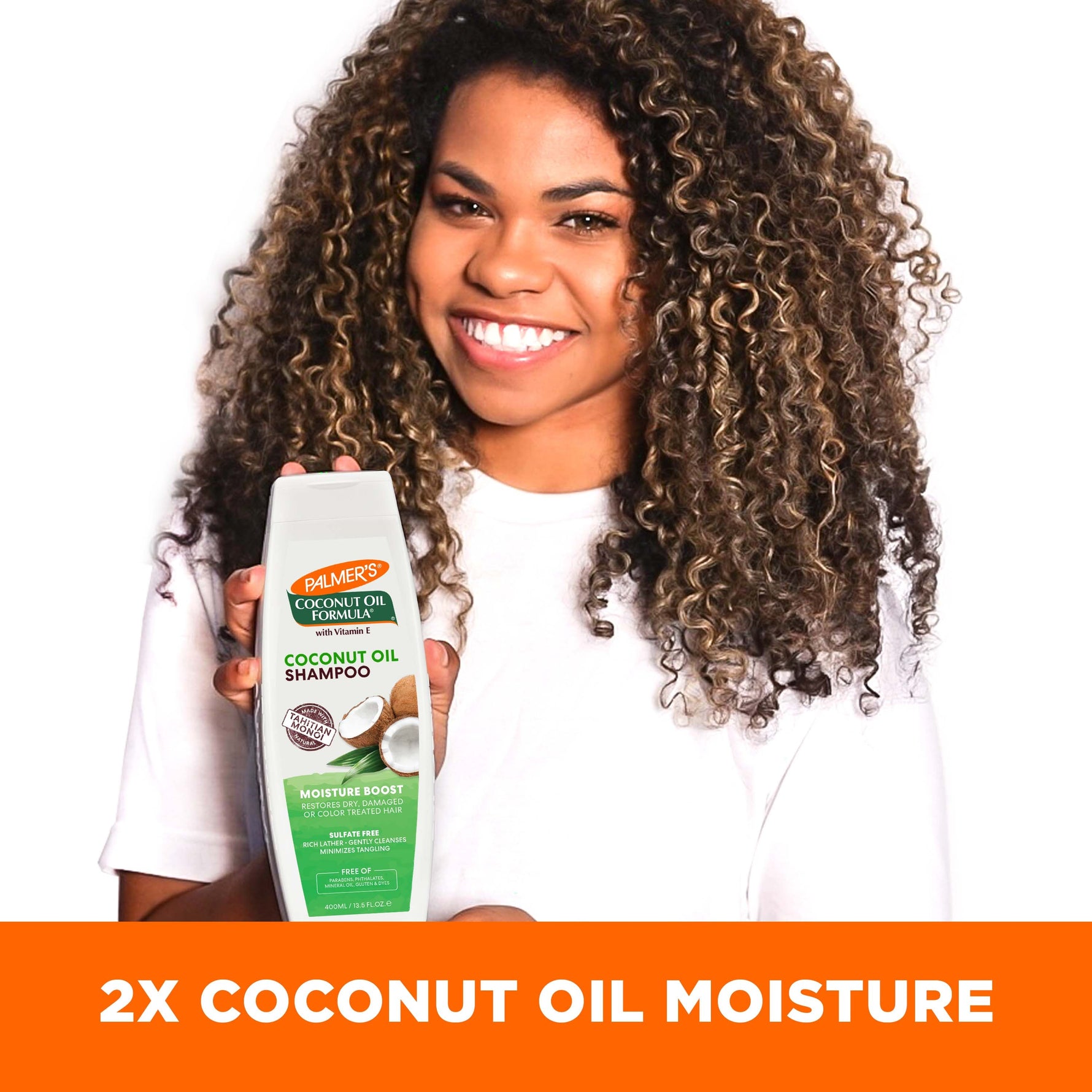 Person smiling, holding Palmer’s Coconut Oil Shampoo, emphasizing moisture boost.