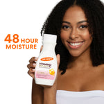 Woman holding Palmer’s Vitamin E Body Lotion, smiling.