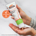Holding Palmer’s Cocoa Butter Massage Cream for Stretch Marks tube.