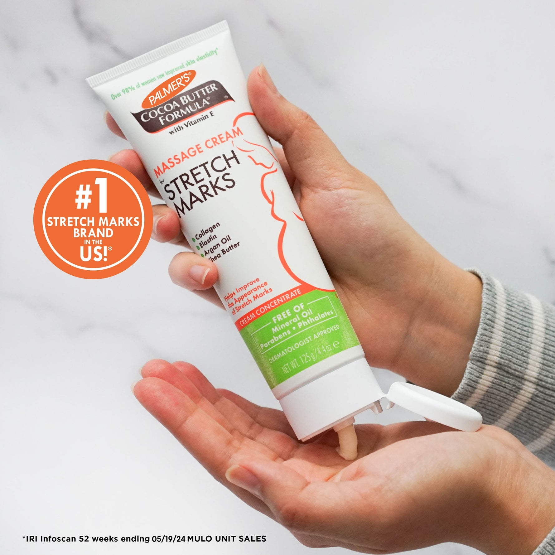 Holding Palmer’s Cocoa Butter Massage Cream for Stretch Marks tube.