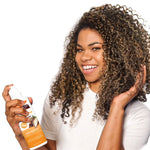 Woman with curly hair holding a bottle of hair care product on a white background