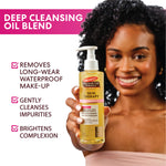 Woman holding a bottle of Palmers Skin Therapy Cleansing Oil with product features listed on a white background