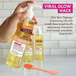 Hand holding a bottle of Palmer's Skin Therapy Cleansing Oil with a soft face brush on a tiled background.