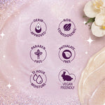 A close-up of a pale pink gel with six dark purple certification-style icons reading 'Derm Approved,' 'Non-Comedogenic,' 'Paraben Free,' 'Phthalate Free,' '72 Hour Moisture,' and 'Vegan Friendly.' Decorative white flowers and sparkles appear in the corners on a glittery pink background.