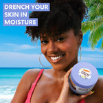 Woman holding a container of Palmer's Tahitian Vanilla Body Balm with a beach background and text 'Drench Your Skin in Moisture'.