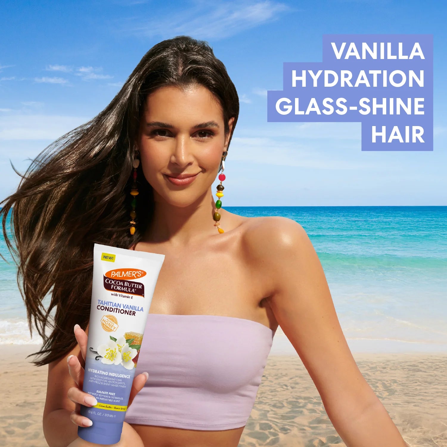 Woman holding a bottle of Palmers Cocoa Butter Formula Tahitian Vanilla Conditioner on a beach with text about vanilla hydration glass-shine hair.