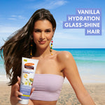 Woman holding a bottle of Palmers Cocoa Butter Formula Tahitian Vanilla Shampoo on a beach with text about vanilla hydration glass-shine hair.