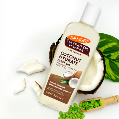 Palmer's Coconut Hydrate Body Oil for glowing skin on coconut with coconut pieces and green coffee beans
