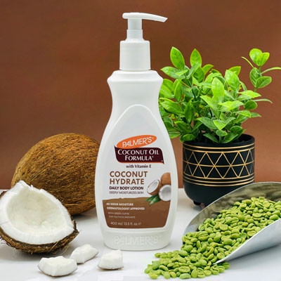 Palmer's Coconut Hydrate Body Lotion for dull and dry skin on table with coconuts and green coffee beans