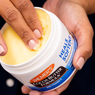 Fingers scooping product out of Palmer's Cocoa Butter Jar as part of summer skin care routine