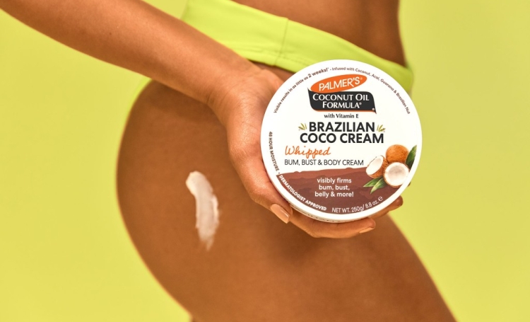 Woman in bikini bottoms holding Palmer's Brazilian Coco Cream, the best way how to reduce cellulite at home